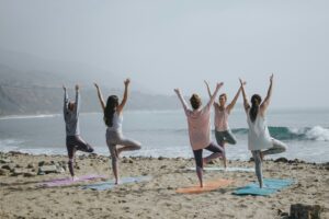 personnes en train de pratiquer le qi gong sur la plage pour améliorer son bien-être holistique